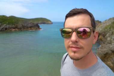 Güneş gözlüğü takan bir çocuk denizden yansıyan biriyle.