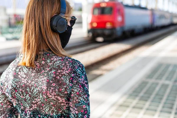 A young beautiful girl wearing the face mask is waiting for the train alone at the train station in Lisbon, Portugal