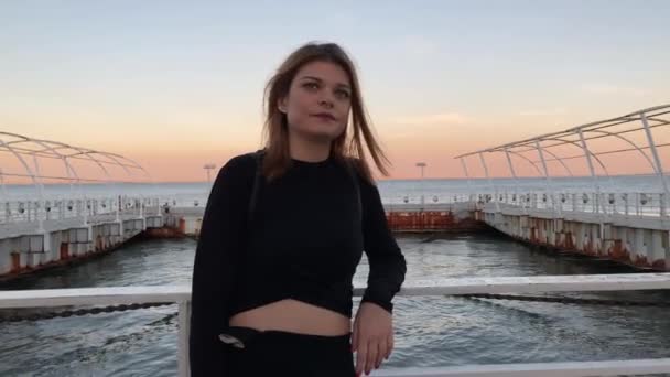 Gyönyörű játékos nő visel egy sötét elegáns ruhát, és elszív egy cigarettát a Lisszabon Tagus folyó vízpartján naplementekor. Gyönyörű lány pihen és nézi a tengert. Életmód szóló nő 