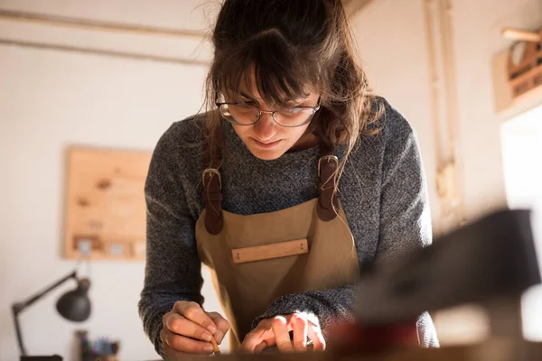 A young female carpenter drawing on a piece of timber while working with wood in a carpentry workshop. Young girl wood worker designing a new piece of furniture. Interior design concept