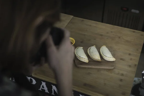 A young and attractive female photographer shooting on a set some pictures of the typical spanish and Argentinian Empanada. Young freelance food photographer at work in a small restaurant in Lisbon