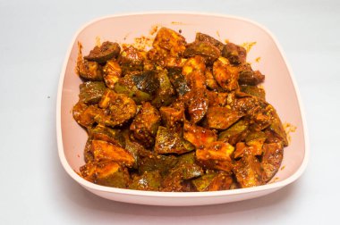 Beyaz arka planda plastik kasede mango turşusu.