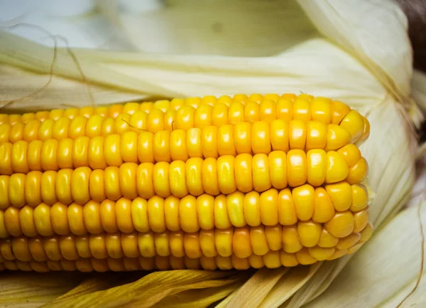 Kurumuş yapraklarla bulanık arka planda çiğ mısır yakın