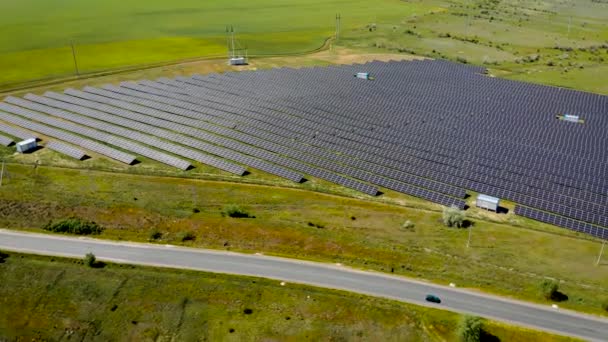 Biler som kjører på vei forbi solcelleanlegg for produksjon av grønn økologisk elektrisk kraft nær landbruksfelt – stockvideo