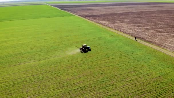 Vue aérienne du drone d'un agriculteur sur un tracteur pulvérisant des cultures et se déplaçant vers le bord du champ 
