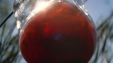 Kırmızı şarap cam kadehte güneş ışınlarının arka planına karşı ağır çekimde sıçrar.