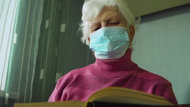 Close up senior caucásico mujer en máscara protectora en su cara lectura libro temas de jubilado pensionista y pasar página — Vídeo de stock