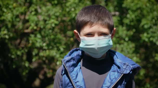 Retrato de niño triste serio en máscara protectora para la prevención del coronavirus mira a la cámara — Vídeo de stock