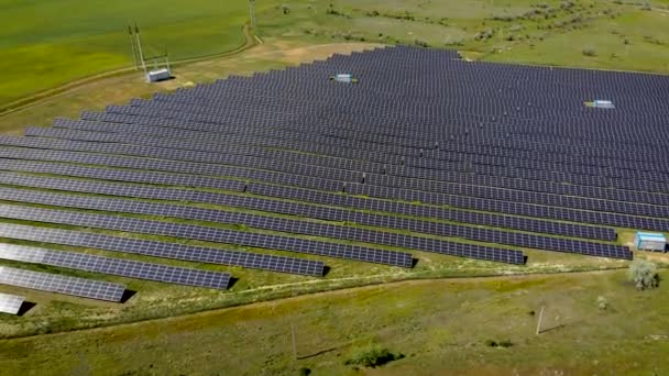 Filmati aerei di centinaia di moduli solari o pannelli per generare filari di elettricità ecologica lungo campi agricoli verdi — Video Stock