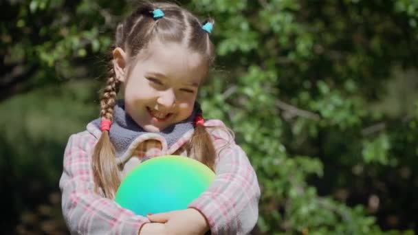 Linda niña alegre con bola de colores en el patio trasero de casa — Vídeo de stock