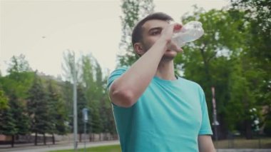 Ağır kardiyo egzersizinden sonra erkek sporcu vücudundaki nemi tazelemek için plastik şişeden su içiyor.