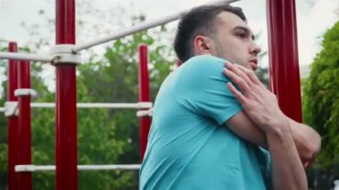 Erkek sporcu şehir parkında sıkı çalıştıktan sonra ısınıyor.