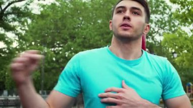 Koyu renk saçlı, formalı erkek açık havada ısınıyor. Kollarını sallıyor, daireler çiziyor ve göğüs genişletme egzersizleri yapıyor.