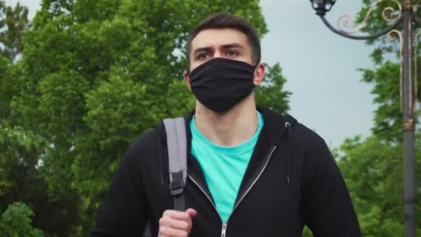 Portret van een jonge toerist met een beschermend gezichtsmasker lopend in het stadspark — Stockvideo