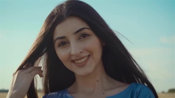 Gros plan portrait de belle femme caucasienne aux cheveux longs souriant à la caméra sur fond de champs de culture — Video