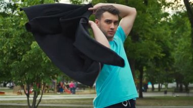 Yakışıklı adam ceketini omuzlarının üzerinden ağır çekimde fırlatıyor.