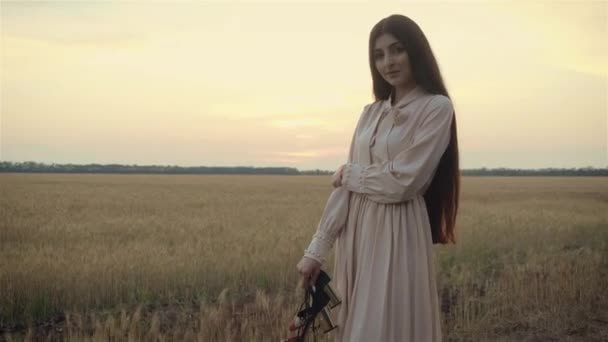 Красивая улыбающаяся уверенная молодая женщина с красивым лицом, смотрящая в камеру и позируя в одиночестве в поле вечером — стоковое видео