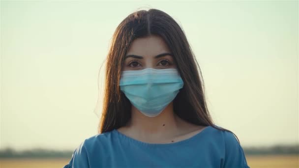 Retrato de mujer joven en máscara médica protectora en la cara en vestido azul — Vídeo de stock