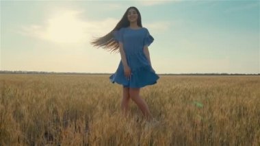 Genç Avrupalı kadın tarımın ortasında kollarını açarak dönüyor.