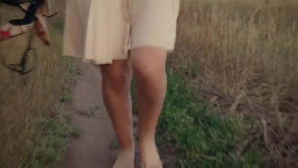 Nahaufnahme von Frauenbeinen, die auf einem Feld zwischen grünem Gras und trockenem Weizen laufen — Stockvideo