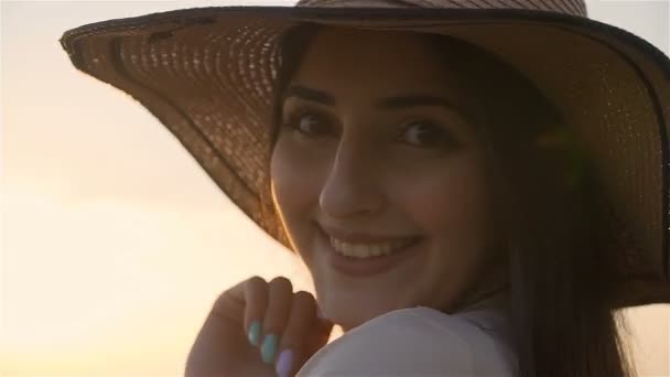 Portrait de belle femme sourit debout seul dans un chapeau de paille debout seul au coucher du soleil — Video