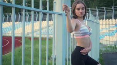 Koşu yaptıktan sonra stadyumun yakınında dinlenen genç bir kadın. Güzel bayan sporcu bir kardiyo egzersizinden sonra yorgun düştü.