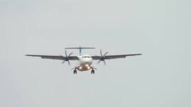 Pervane düzlemi iniş için yavaşça yaklaşıyor. Uçaklar sürekli olarak bulutlu gökyüzüne iniyor. Sakin iniş prosedürünü gösteren yumuşak bir yaklaşım.