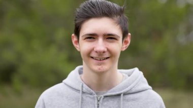 Ergenlik çağında dışarıda gülümseyen genç sivilceli mutlu bir çocuk portresi. Sivilceli neşeli bir ergen, açık havada gülümsüyor, ergenlik çağında. Ergenlik çağında, temiz havada sırıtan neşeli, genç bir çocuk.