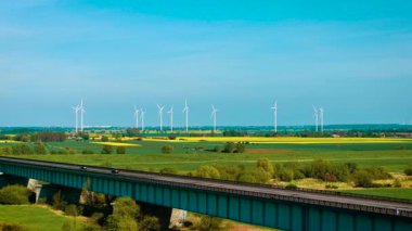 Rüzgar türbinleri yeşil alanlar boyunca ekolojik elektrik üretiyor. Rüzgar jeneratörleri dönen bıçaklarla sürdürülebilir enerji üretiyor. Yel değirmenleri dönen kolları kullanarak temiz enerji üretiyor.