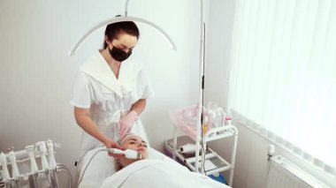 Kozmetik uzmanı, sağlık merkezindeki işlem sırasında ultrason dezenfekte cihazı kullanıyor. Dişi uzman, daha pürüzsüz ve tazelenmiş cilt için nazikçe deri yüzüyor. Bayan Güzellik Uzmanı müşteri için etkili cilt bakımı sağlıyor