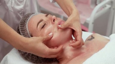 Kozmetoloji uzmanı güzellik tedavisi sırasında masaj tekniklerini nazikçe uyguluyor. Estetik merkezde gençleştirme terapisi. Geliştirilmiş deri dokusu için yüz prosedürü uygulayan bir terapist.