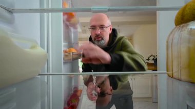 Buzdolabını açan, doğal ifadeyle süt içen, buzdolabının içini gören bir adam. Erkek kendini sakin ve odaklanmış hissederken hızlı bir içki içiyor. Camdan yudumlayan, rahat ve düşünceli görünen bir adam.