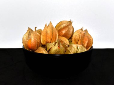 Siyah ve beyaz arka planda siyah kasede yenilebilir bitki özü.