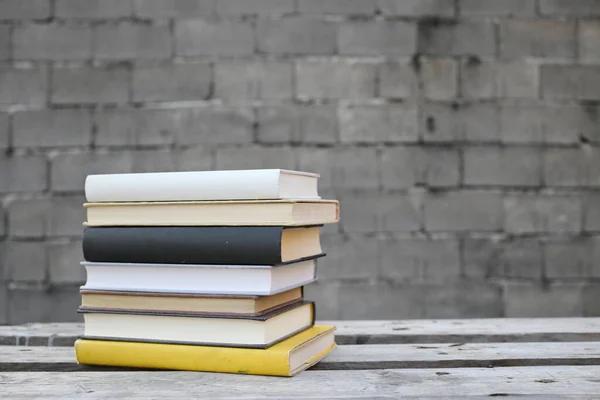 Books on a wooden bench in front of a wall