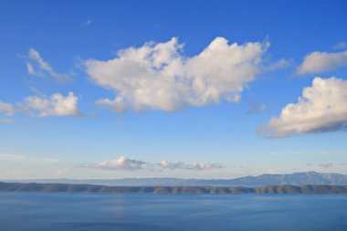 Denizin üstündeki mavi gökyüzünde beyaz bulutlar