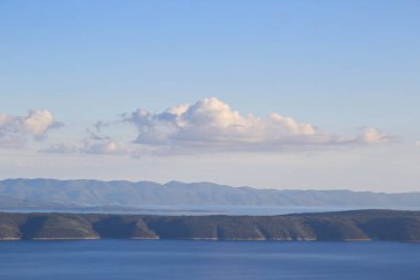 Denizin üstündeki mavi gökyüzünde beyaz bulutlar