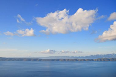 Denizin üstündeki mavi gökyüzünde beyaz bulutlar