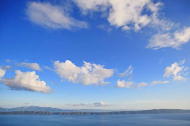 Denizin üstündeki mavi gökyüzünde beyaz bulutlar
