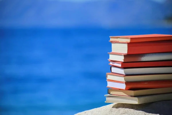 Stack of books on a stone pillar by the sea