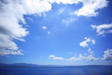 Denizin üstündeki mavi gökyüzünde beyaz bulutlar