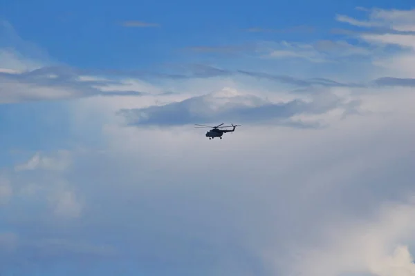 Helicopter in flight in the blue sky under the clouds