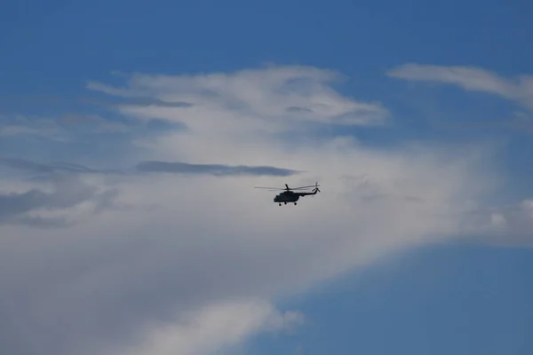 Helicopter in flight in the blue sky under the clouds