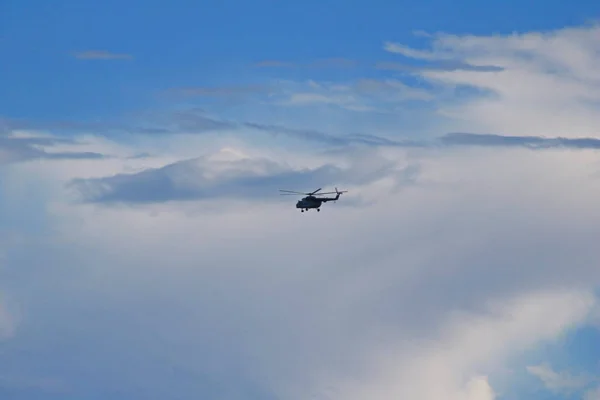 Helicopter in flight in the blue sky under the clouds