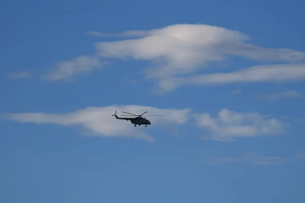 Helicopter in flight in the blue sky under the clouds