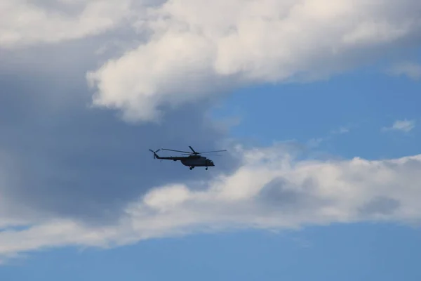 Helicopter in flight in the blue sky under the clouds