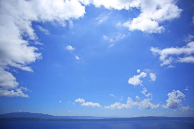 Denizin üstündeki mavi gökyüzünde beyaz bulutlar