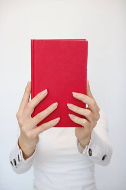 Genç bir kız elinde bir kitap tutuyor.