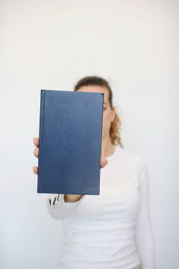 Genç bir kız elinde bir kitap tutuyor.