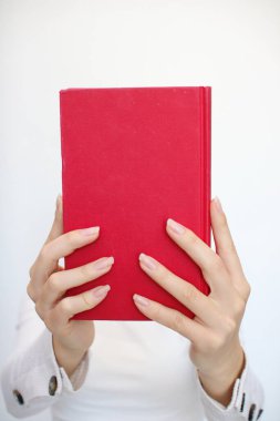 Genç bir kız elinde bir kitap tutuyor.