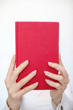 Genç bir kız elinde bir kitap tutuyor.